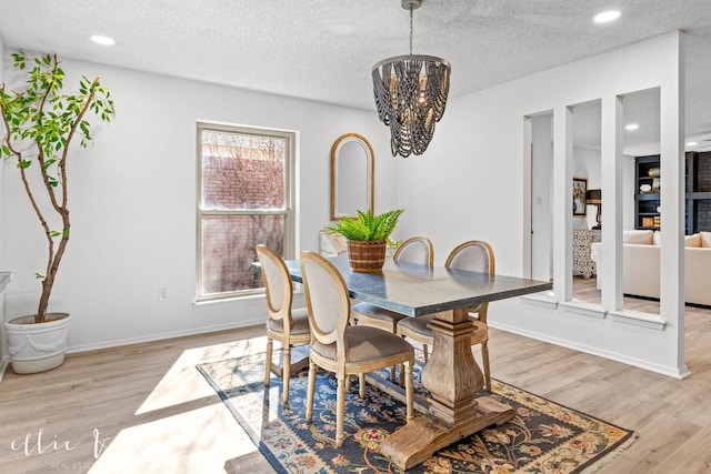 dining area featuring a chandelier, light hardwood / wood-style floors, and a textured ceiling