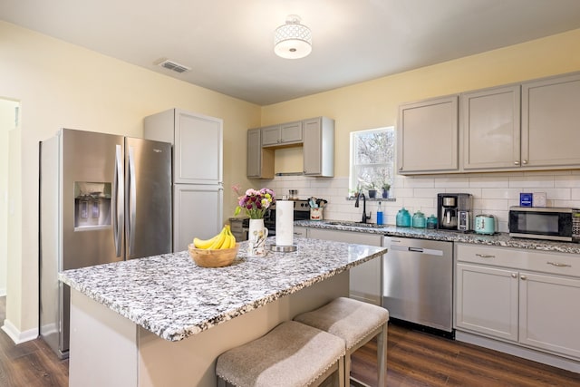 kitchen with sink, dark hardwood / wood-style floors, stainless steel appliances, and a center island