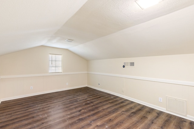 bonus room with vaulted ceiling, dark hardwood / wood-style floors, and a textured ceiling