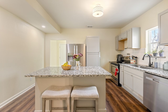 kitchen with a center island, appliances with stainless steel finishes, sink, and light stone counters