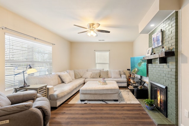 living room with a brick fireplace, ceiling fan, and light hardwood / wood-style flooring