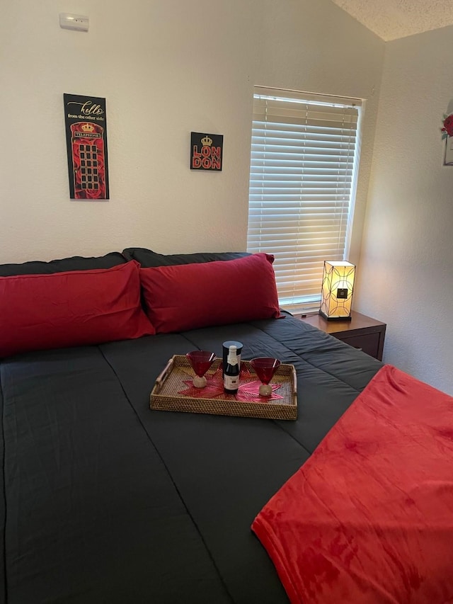 bedroom featuring vaulted ceiling and a textured ceiling