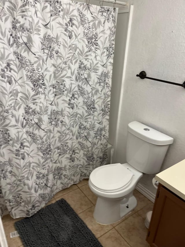 bathroom with vanity, toilet, tile patterned floors, and walk in shower