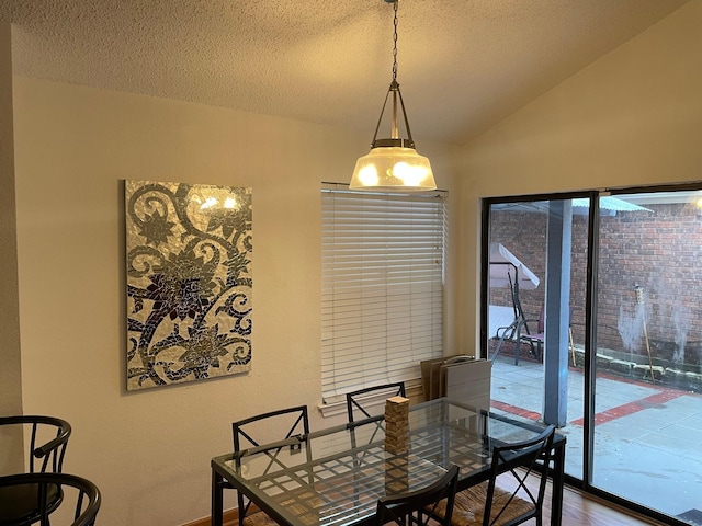 dining space with vaulted ceiling and a textured ceiling