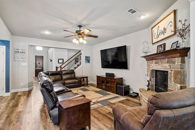 living room with a fireplace, ceiling fan, and light hardwood / wood-style flooring