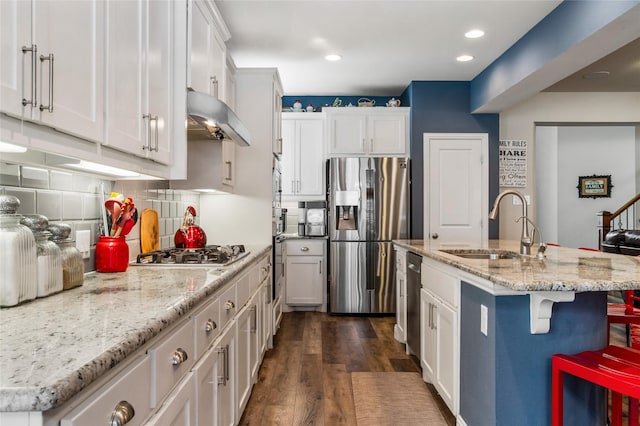 kitchen featuring sink, stainless steel appliances, white cabinetry, and a breakfast bar area