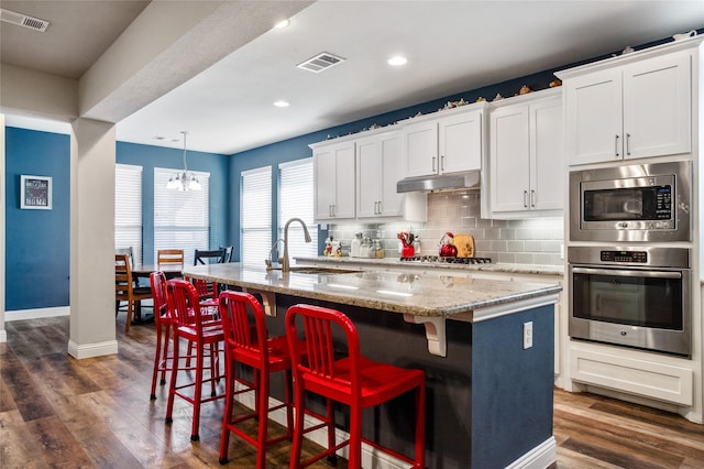 kitchen with sink, white cabinets, an island with sink, light stone countertops, and appliances with stainless steel finishes