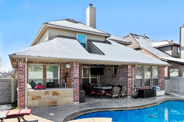 rear view of property featuring a patio area and a fenced in pool