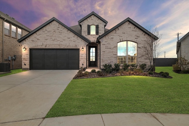 french country home with a garage, a yard, and central air condition unit