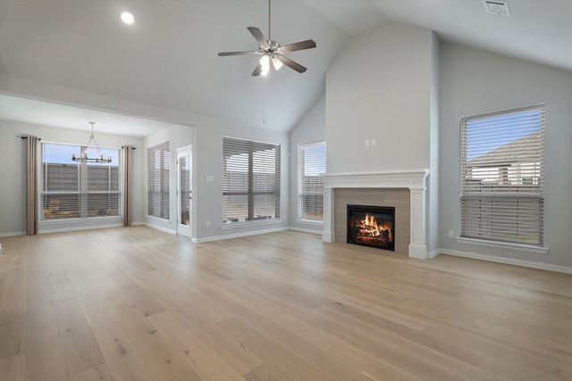 unfurnished living room featuring light wood-type flooring, ceiling fan with notable chandelier, lofted ceiling, and a tiled fireplace