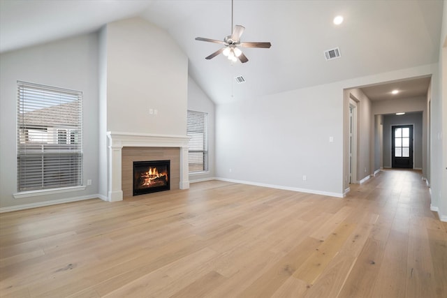 unfurnished living room featuring high vaulted ceiling, light hardwood / wood-style flooring, ceiling fan, and a tiled fireplace