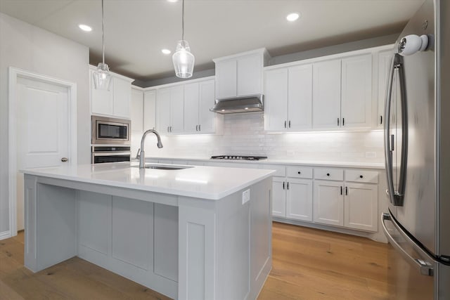 kitchen with sink, an island with sink, decorative light fixtures, white cabinetry, and stainless steel appliances