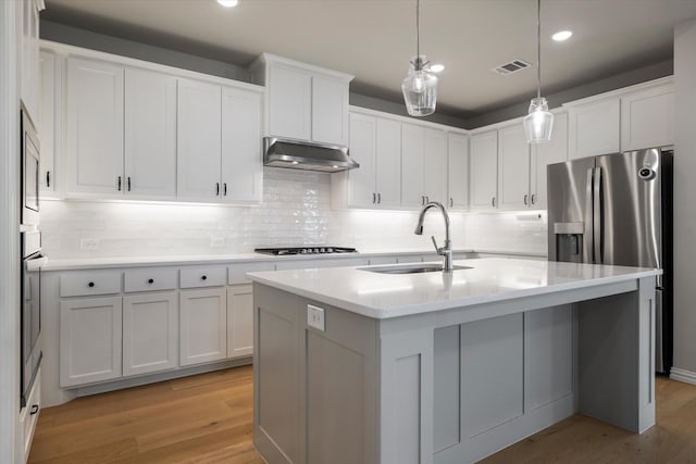 kitchen with white cabinets, light hardwood / wood-style flooring, sink, and an island with sink