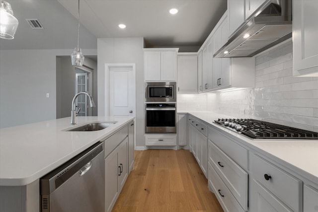 kitchen featuring white cabinetry, sink, wall chimney exhaust hood, stainless steel appliances, and pendant lighting