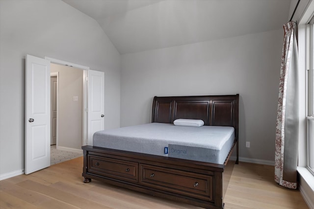 bedroom with light hardwood / wood-style floors and lofted ceiling