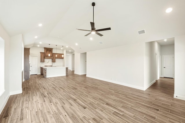 unfurnished living room with vaulted ceiling, ceiling fan, light wood-style flooring, baseboards, and visible vents