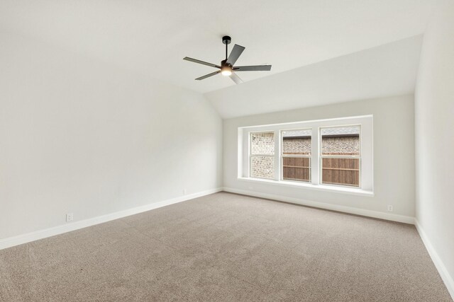 carpeted empty room featuring lofted ceiling, baseboards, and ceiling fan