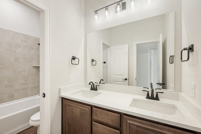 bathroom with bathing tub / shower combination, a sink, double vanity, and toilet