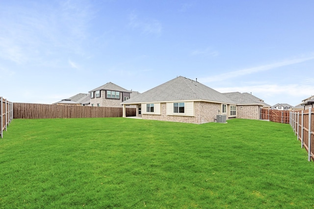 back of house featuring a fenced backyard, a yard, and central air condition unit