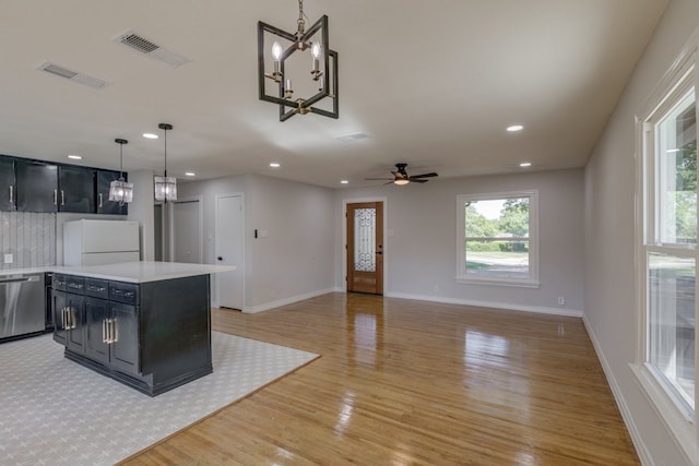 kitchen with light wood-type flooring, stainless steel dishwasher, ceiling fan with notable chandelier, decorative light fixtures, and white fridge