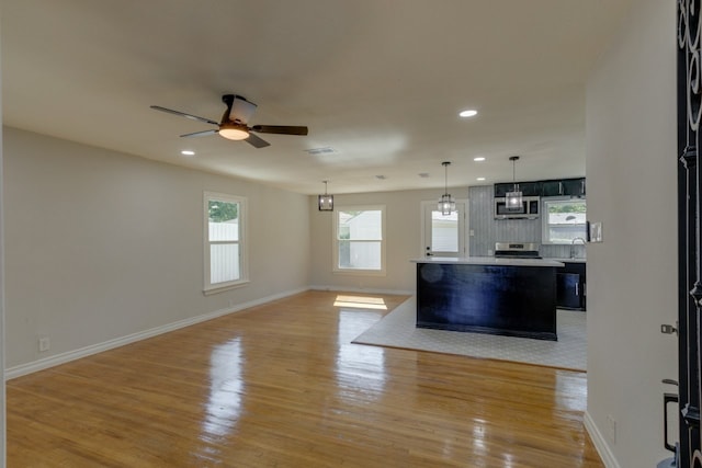 unfurnished living room featuring ceiling fan, light hardwood / wood-style flooring, and sink