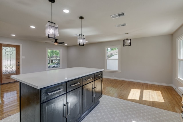 kitchen with ceiling fan, a center island, a wealth of natural light, and decorative light fixtures