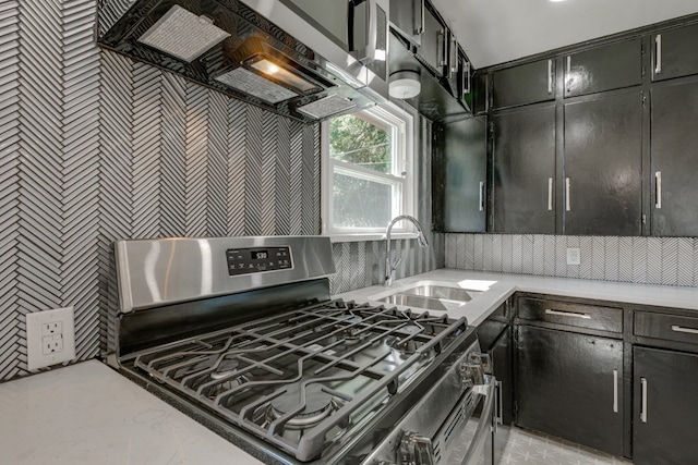 kitchen featuring stainless steel gas stove, range hood, and sink