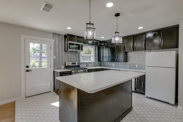 kitchen with pendant lighting, a kitchen island, a healthy amount of sunlight, and stainless steel appliances