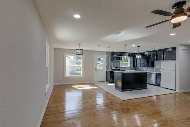 kitchen featuring a center island, hanging light fixtures, light wood-type flooring, tasteful backsplash, and stainless steel appliances