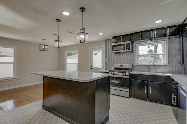 kitchen featuring pendant lighting, a center island, sink, appliances with stainless steel finishes, and light hardwood / wood-style floors