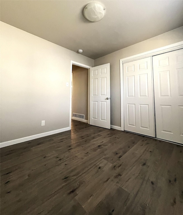 unfurnished bedroom featuring a closet and dark hardwood / wood-style floors