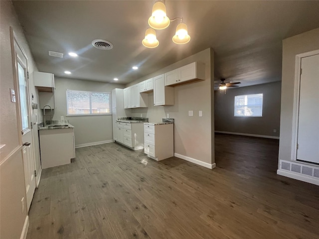 kitchen with light wood-type flooring, ceiling fan with notable chandelier, a healthy amount of sunlight, sink, and white cabinetry