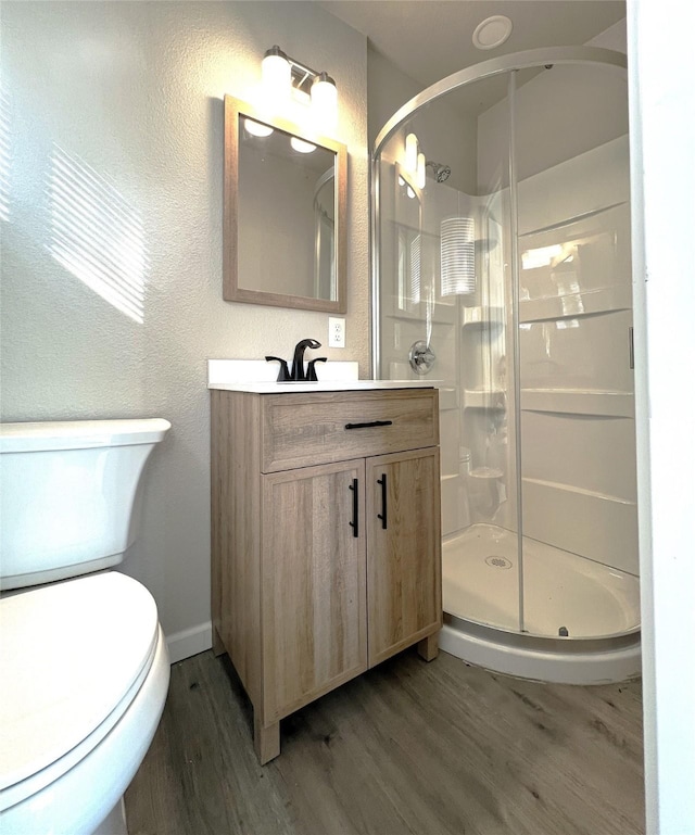 bathroom with vanity, hardwood / wood-style flooring, a shower with door, and toilet