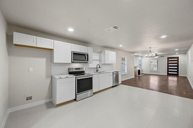 kitchen featuring white cabinets, ceiling fan with notable chandelier, sink, hanging light fixtures, and stainless steel appliances