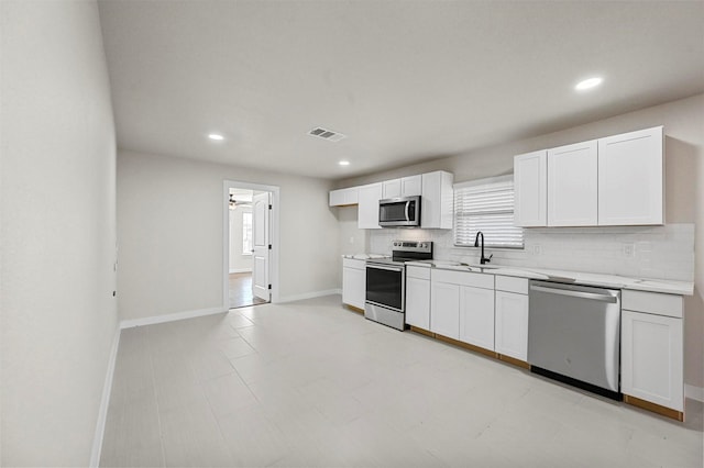 kitchen with white cabinets, appliances with stainless steel finishes, ceiling fan, and sink