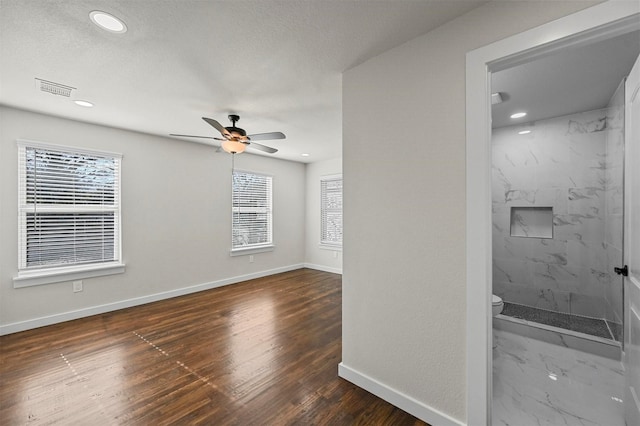 interior space with dark hardwood / wood-style floors, ceiling fan, and a textured ceiling