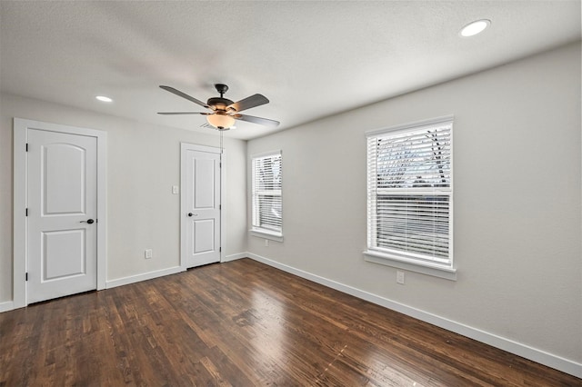 unfurnished bedroom with ceiling fan and dark wood-type flooring