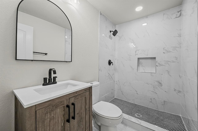 bathroom with vanity, toilet, and tiled shower