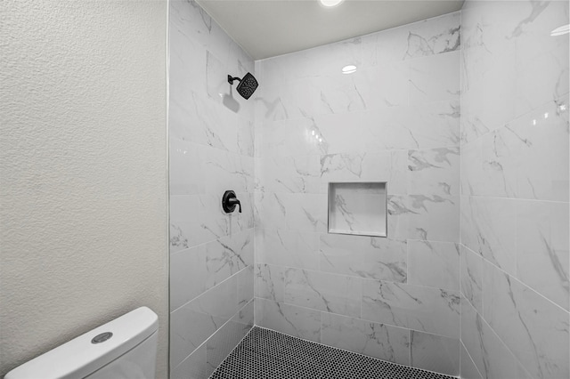 bathroom featuring a tile shower and toilet