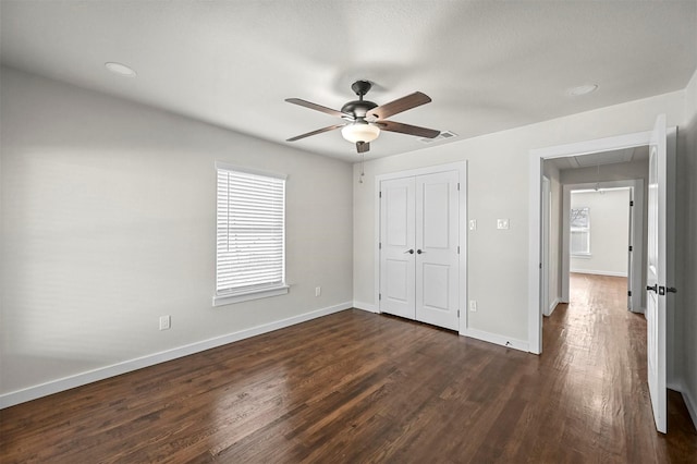 unfurnished bedroom featuring ceiling fan, dark hardwood / wood-style flooring, and a closet