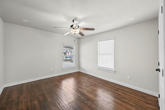 spare room with dark hardwood / wood-style floors, ceiling fan, and a healthy amount of sunlight