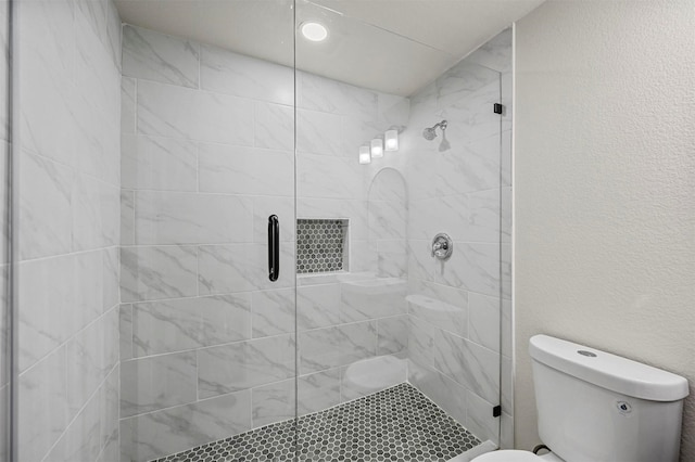 bathroom featuring toilet and a shower with shower door