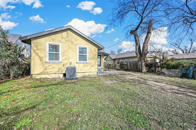 rear view of property featuring a lawn and central AC unit