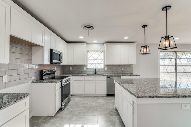 kitchen featuring pendant lighting, white cabinetry, stainless steel appliances, and dark stone counters