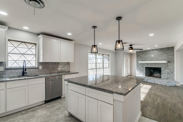 kitchen featuring sink, stainless steel dishwasher, ceiling fan, decorative light fixtures, and white cabinetry