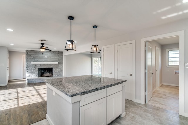 kitchen with plenty of natural light, dark stone countertops, white cabinetry, and hanging light fixtures