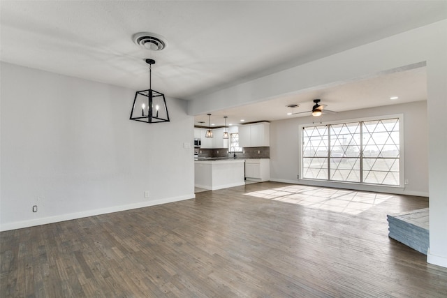 unfurnished living room with ceiling fan with notable chandelier and hardwood / wood-style flooring