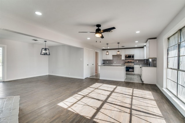 kitchen with a center island, white cabinets, pendant lighting, and appliances with stainless steel finishes