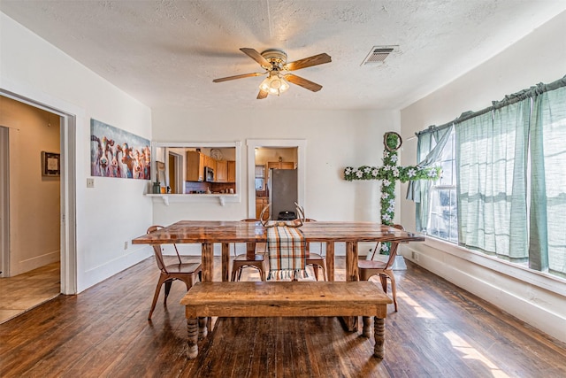 dining room with ceiling fan, dark hardwood / wood-style flooring, and a textured ceiling