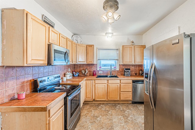 kitchen featuring decorative backsplash, sink, light brown cabinets, and appliances with stainless steel finishes